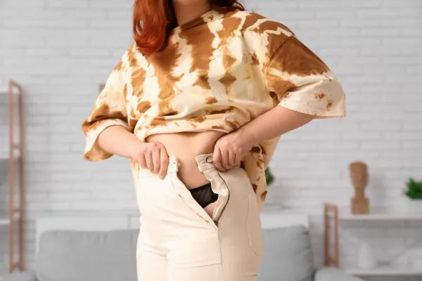 Image of woman trying to do her trousers up after pregnancy weight gain Worksop